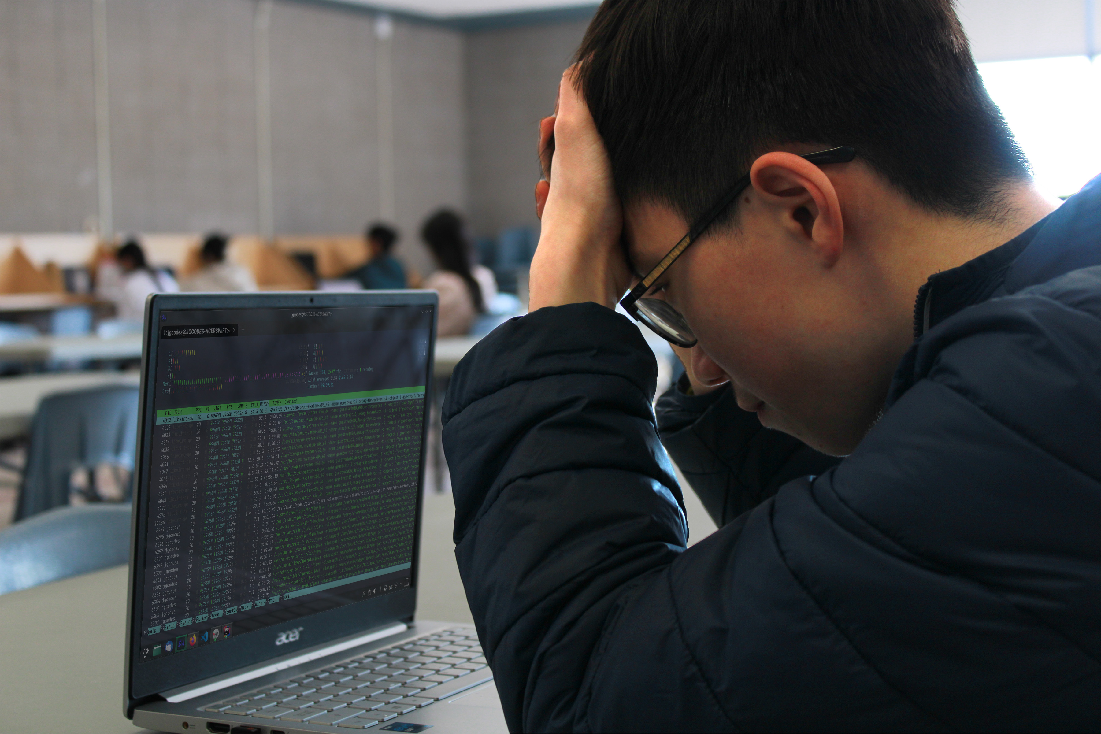 Picture of Jacky, hand against his forehead, in front of his laptop.